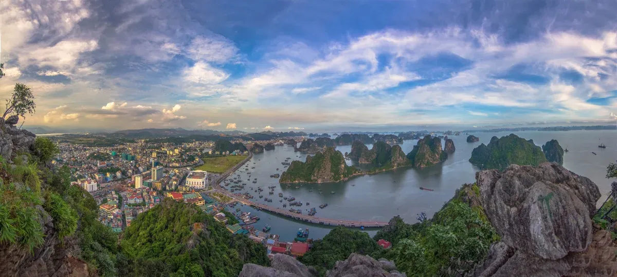 Limestone islands rising from Ha Long Bay behind the town of Ha Long, the bay most Vietnam tour packages build a night around